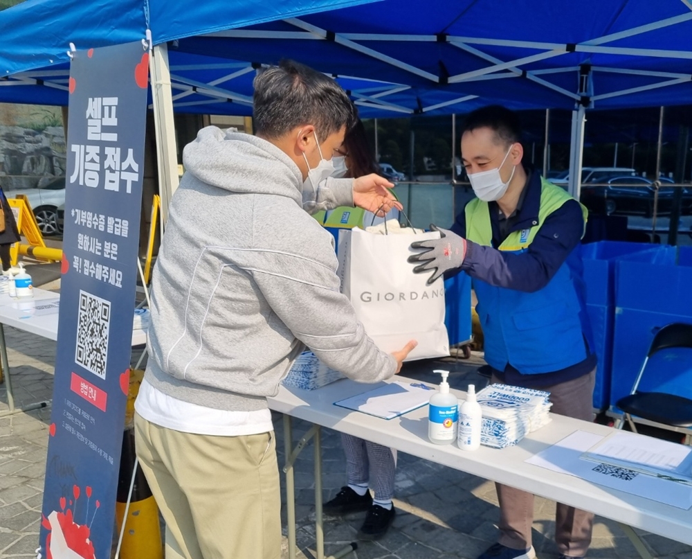 온누리교회 성도가 굿윌스토어 직원에게 기증품을 전달하고 있다.jpg